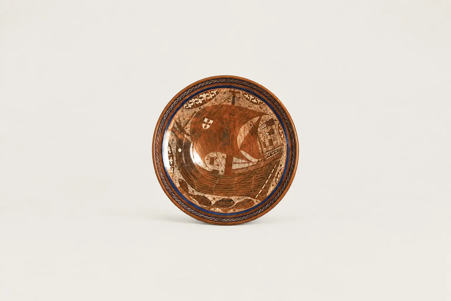 Hand-painted lustreware decorative plate featuring an ornate sailing ship motif in copper brown, cream and cobalt blue.