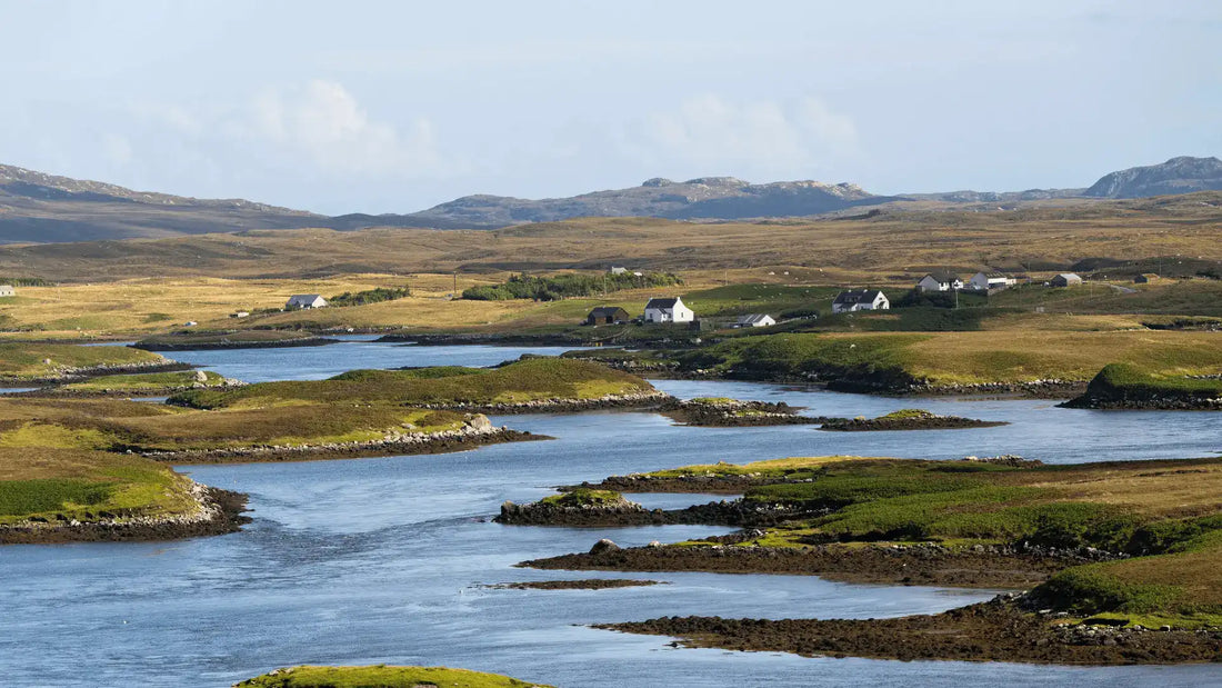 A serene Scottish landscape with rolling hills, scattered cottages, and winding waterways, reflecting the natural beauty that inspires our cashmere and wool throws, woven with care in Scotland.