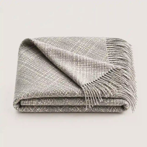 A folded gray woven throw blanket with fringed edges, shown on a plain light gray background.