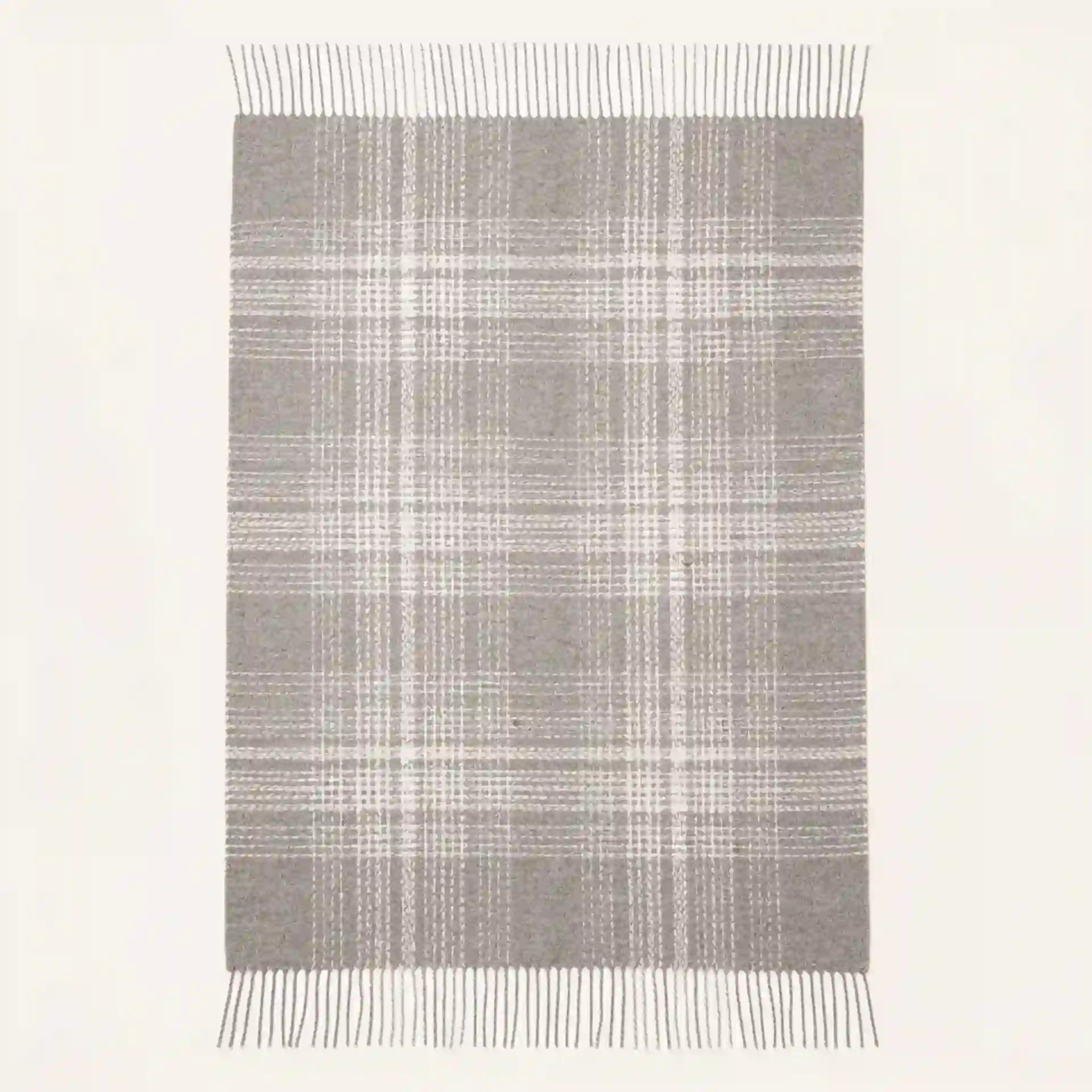 A rectangular throw blanket with a gray and white plaid pattern and fringe on the top and bottom edges, shown against a plain off-white background.