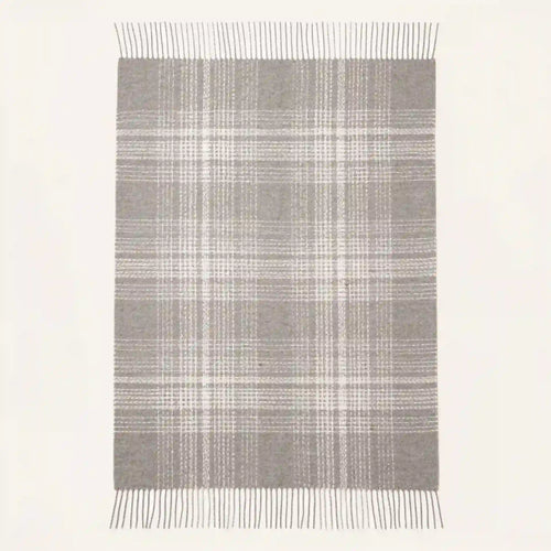 A rectangular throw blanket with a gray and white plaid pattern and fringe on the top and bottom edges, shown against a plain off-white background.