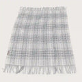 A fringed woven throw blanket with a gray and white plaid pattern, laid flat against a light off-white background.