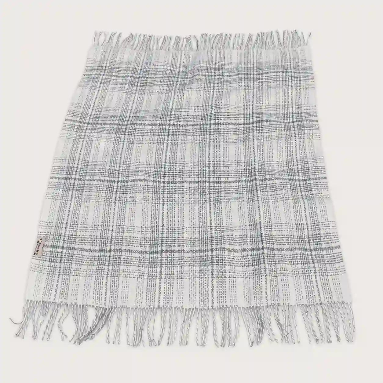 A fringed woven throw blanket with a gray and white plaid pattern, laid flat against a light off-white background.