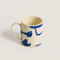 Ceramic mug with blue abstract designs on a light gray background