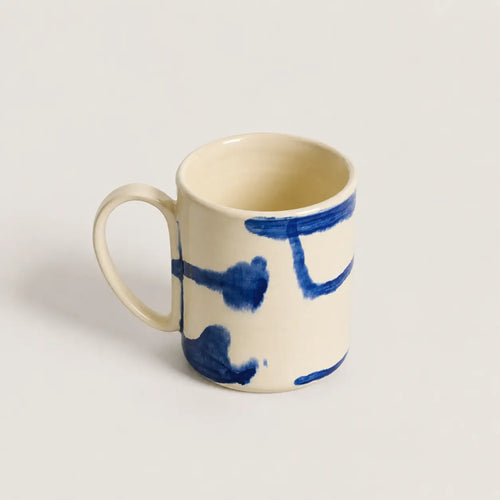 Ceramic mug with blue abstract designs on a light gray background