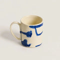 Porcelain mug with blue abstract designs on a light gray background