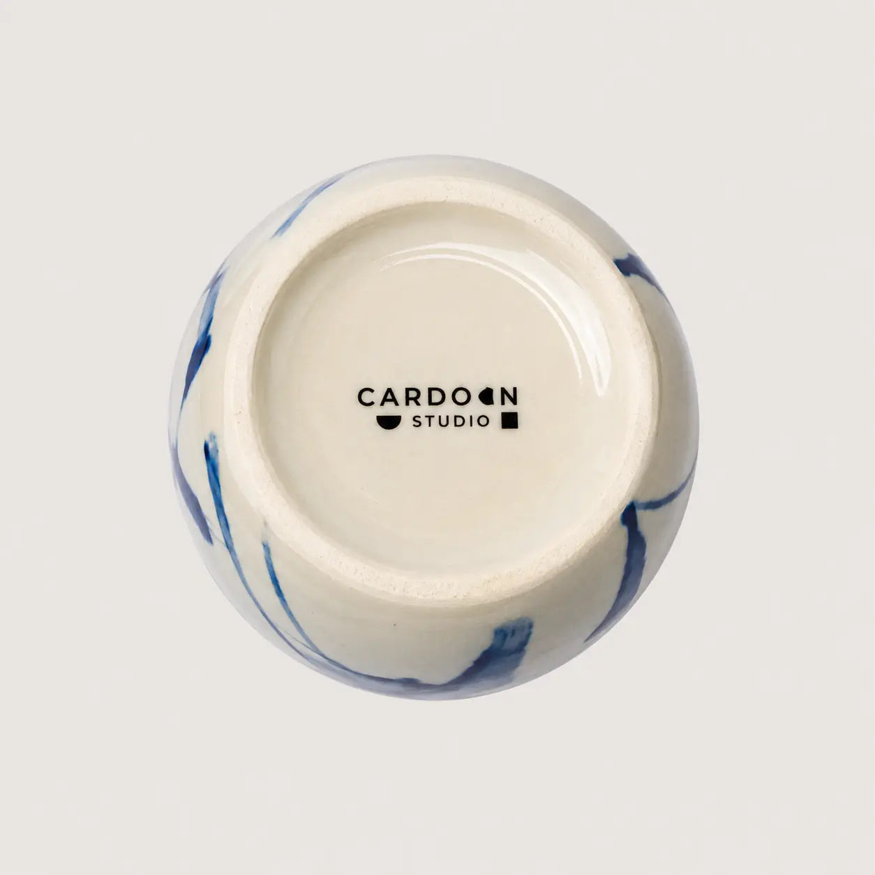 Ceramic container with blue marbled design and 'Cardoon Studio' logo on a light gray background