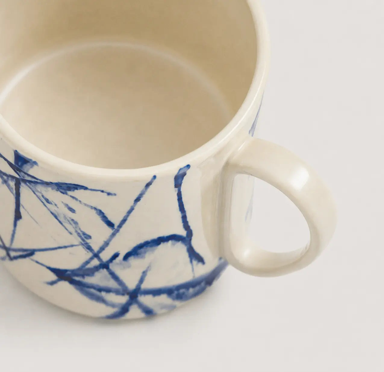 White mug with blue abstract patterns on a light gray background