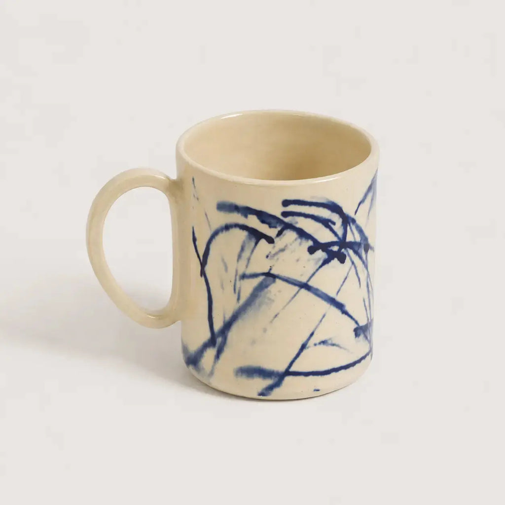 Beige and blue porcelain mug with blue abstract patterns on a white background