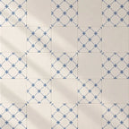 Square ceramic tiles arranged in a grid, featuring alternating patterns of solid cream tiles and tiles with a blue geometric star lattice design.
