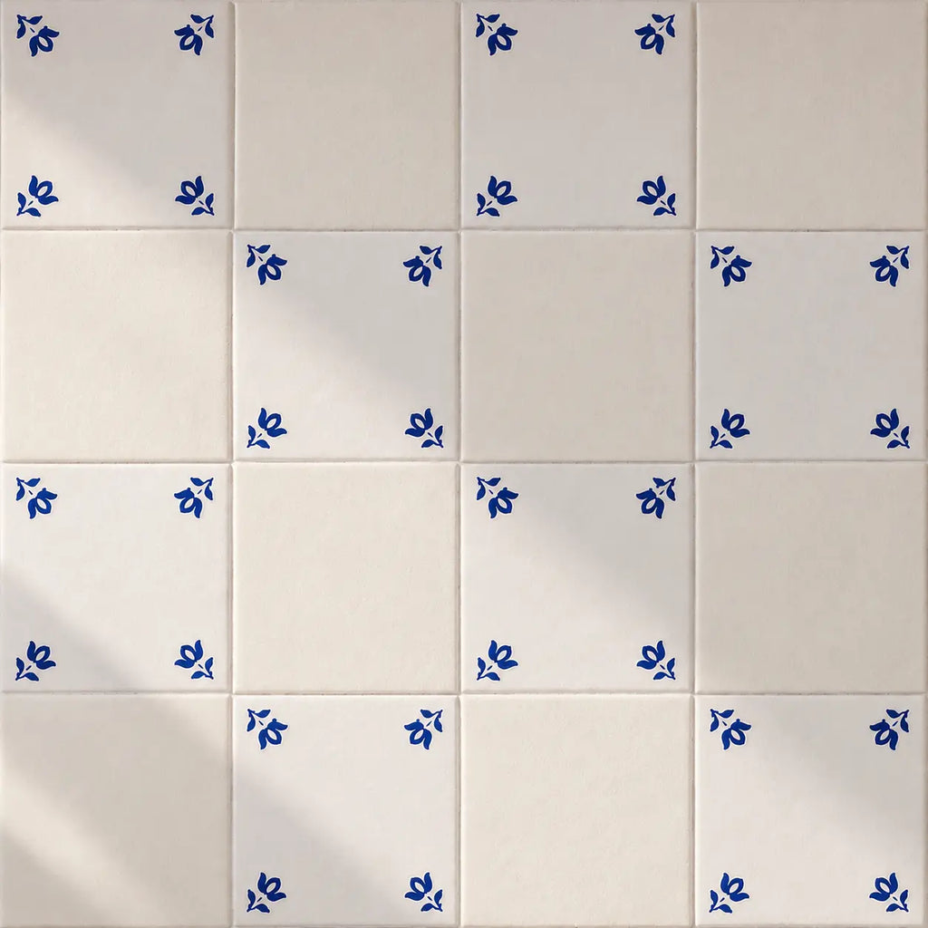 White ceramic tiles arranged in a grid, with several tiles decorated in the corners by small blue floral motifs.
