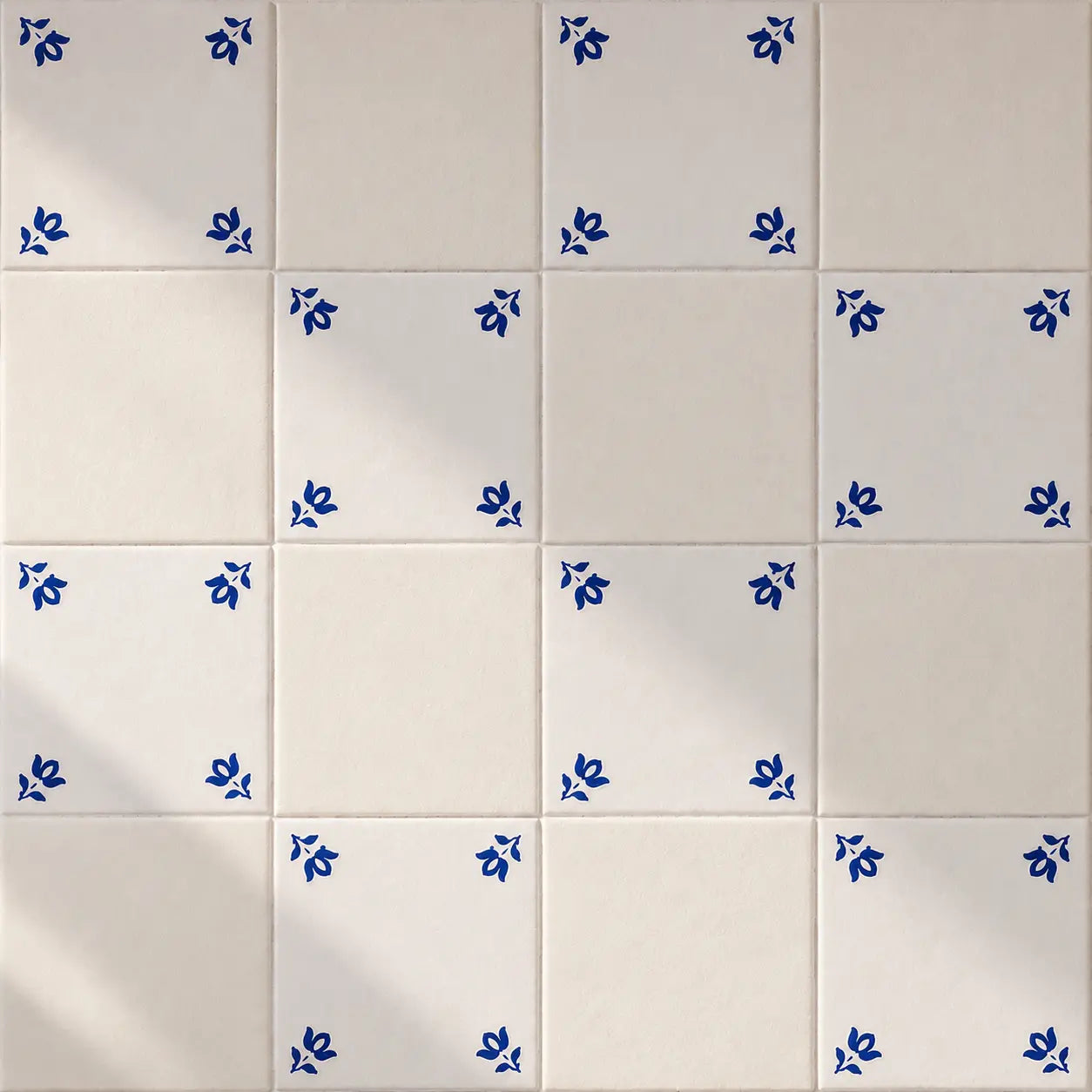 White ceramic tiles arranged in a grid, with several tiles decorated in the corners by small blue floral motifs.