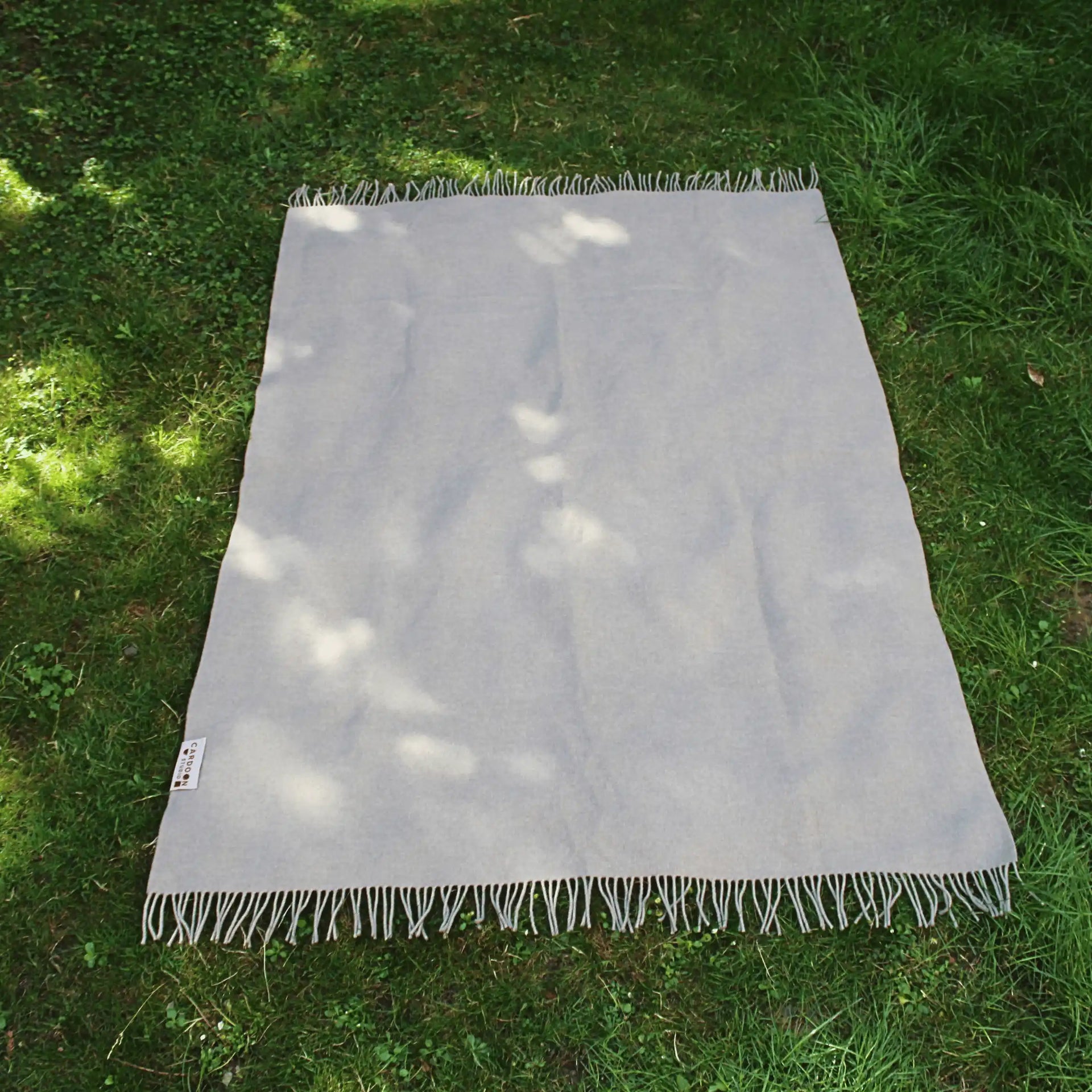 Dothan design throw blanket in taupe colour over a grass garden