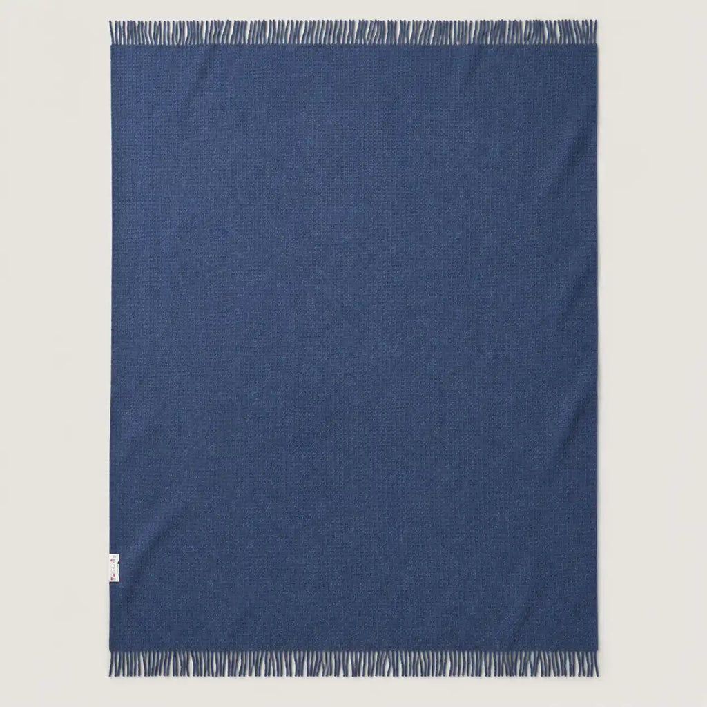 blue textured wool throw blanket laid wide on the floor