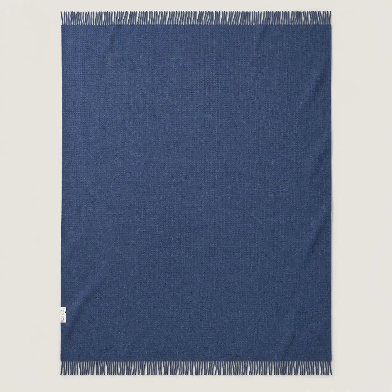 blue textured wool throw blanket laid wide on the floor