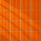 A 4x4 grid of square orange wood-look panels with a brushed texture and thin grout lines, arranged in a clean pattern with soft diagonal shadows.