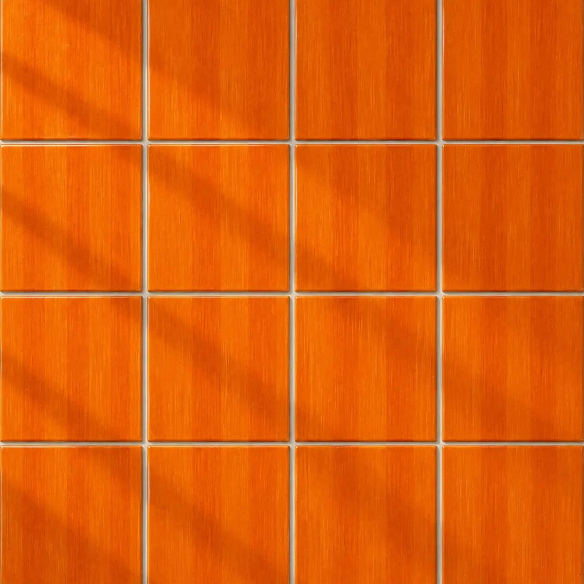 A 4x4 grid of square orange wood-look panels with a brushed texture and thin grout lines, arranged in a clean pattern with soft diagonal shadows.