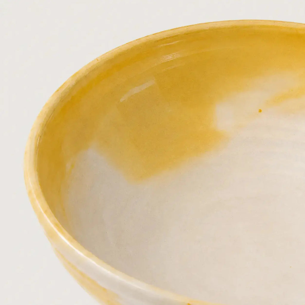Close-up of a ceramic snack bowl showing a glossy yellow glazed interior and a white exterior rim against a plain white background.