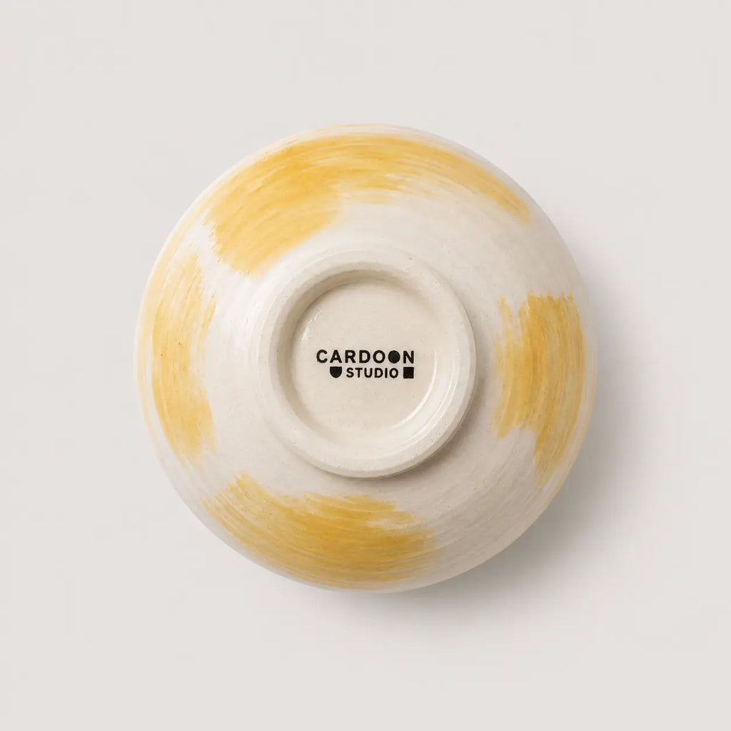 Ceramic snack bowl with yellow and white design on a light gray background, featuring the 'Cardoon Studio' logo.