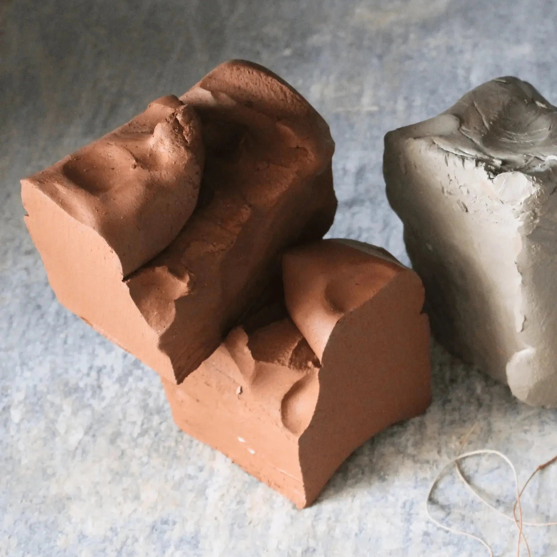 Raw clay blocks and sculptural ceramic materials displayed in an artisanal pottery studio setting.