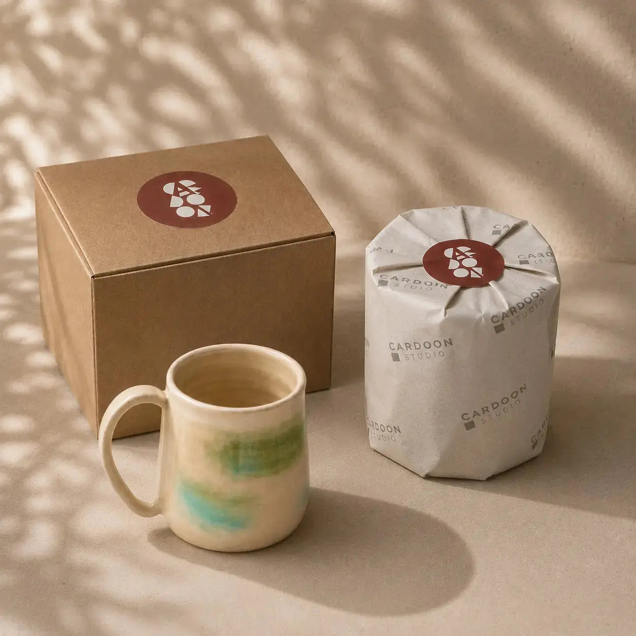 Porcelain mug with a cardboard box and white bag featuring a logo on a beige background