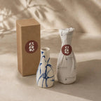 Two ceramic vases and a cardboard box with a brand logo on a beige background