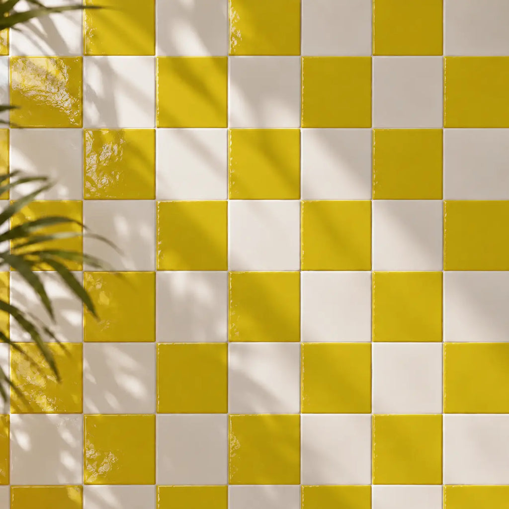 Citron yellow and white checkered tiled wall with soft leaf shadows cast across it.