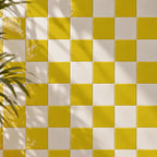 Citron yellow and white checkered tiled wall with soft leaf shadows cast across it.