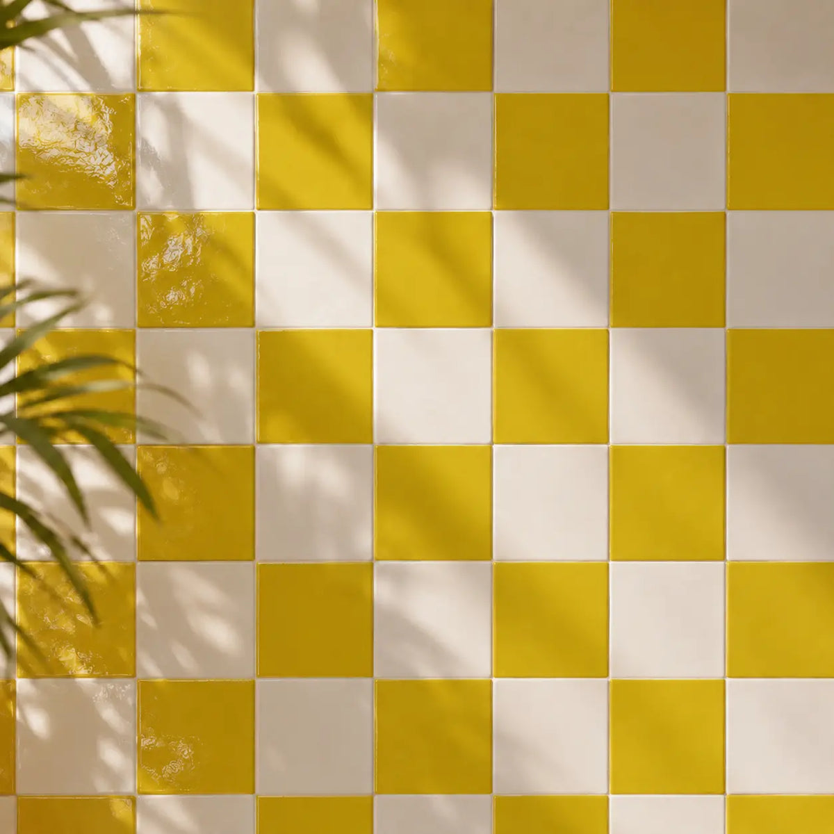 Citron yellow and white checkered tiled wall with soft leaf shadows cast across it.