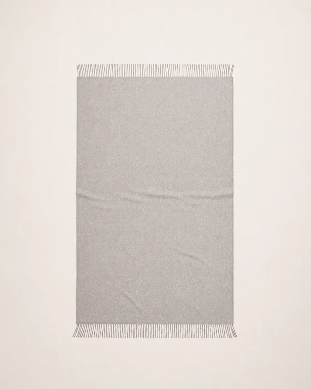An alpaca light gray woven throw blanket with fringed edges, laid flat against a white background.