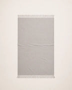 An alpaca light gray woven throw blanket with fringed edges, laid flat against a white background.