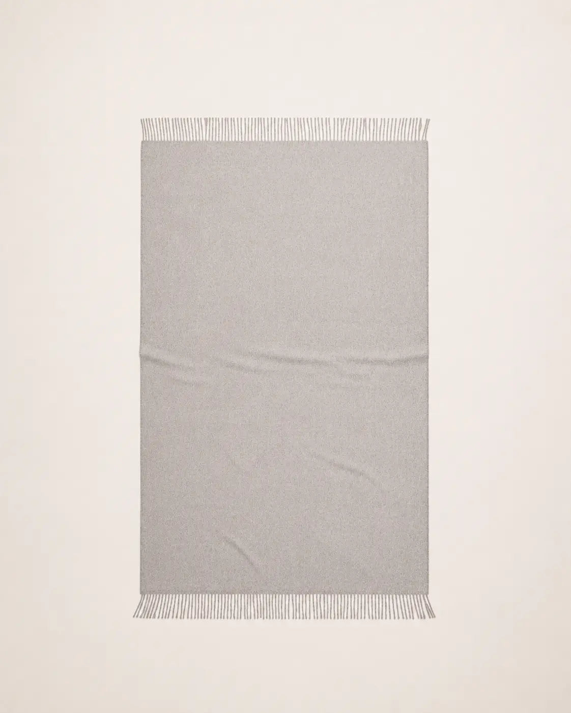 An alpaca light gray woven throw blanket with fringed edges, laid flat against a white background.