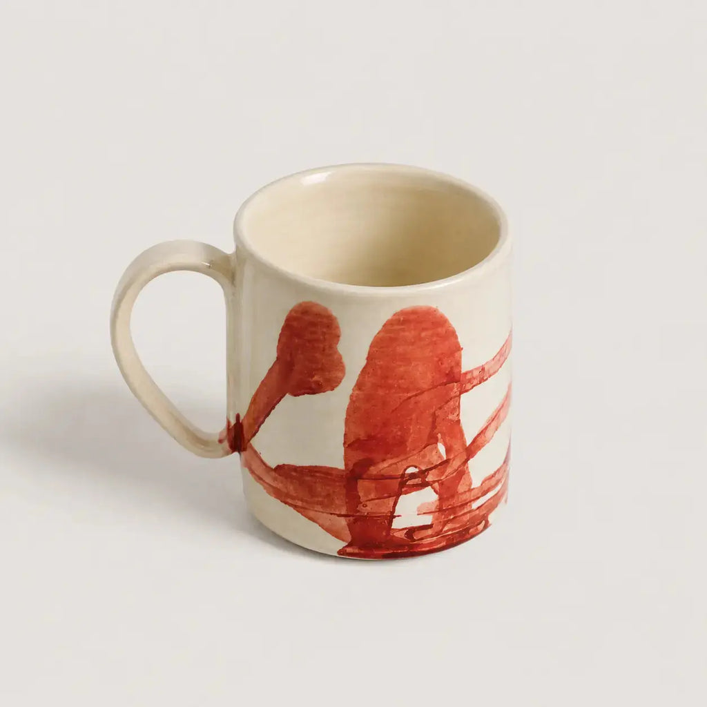 White porcelain mug with red abstract design on a light gray background