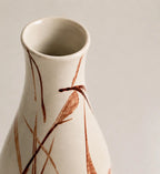 Ceramic vase with brown leaf-like patterns on a plain background