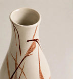 Ceramic vase with brown leaf-like patterns on a plain background