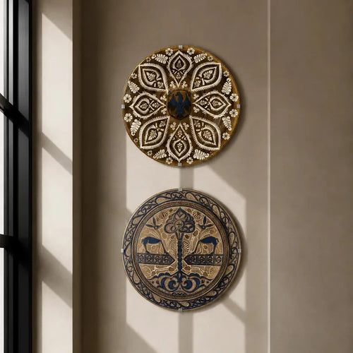 Two circular decorative wall plates with intricate patterns hang on a beige wall above a wooden chair with a woven seat, next to a window with soft sunlight.