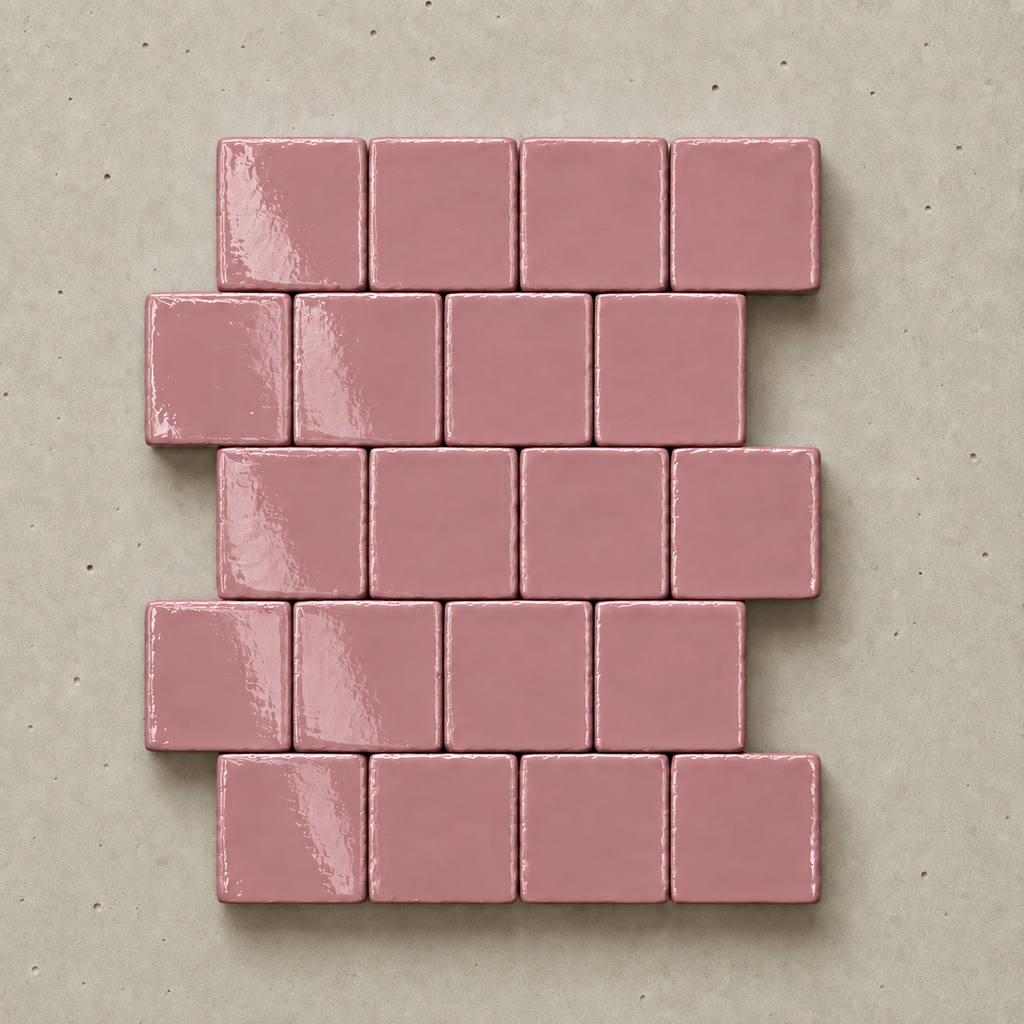 A set of glossy, rectangular dusty pink tiles arranged in a staggered brick pattern on a textured beige background.