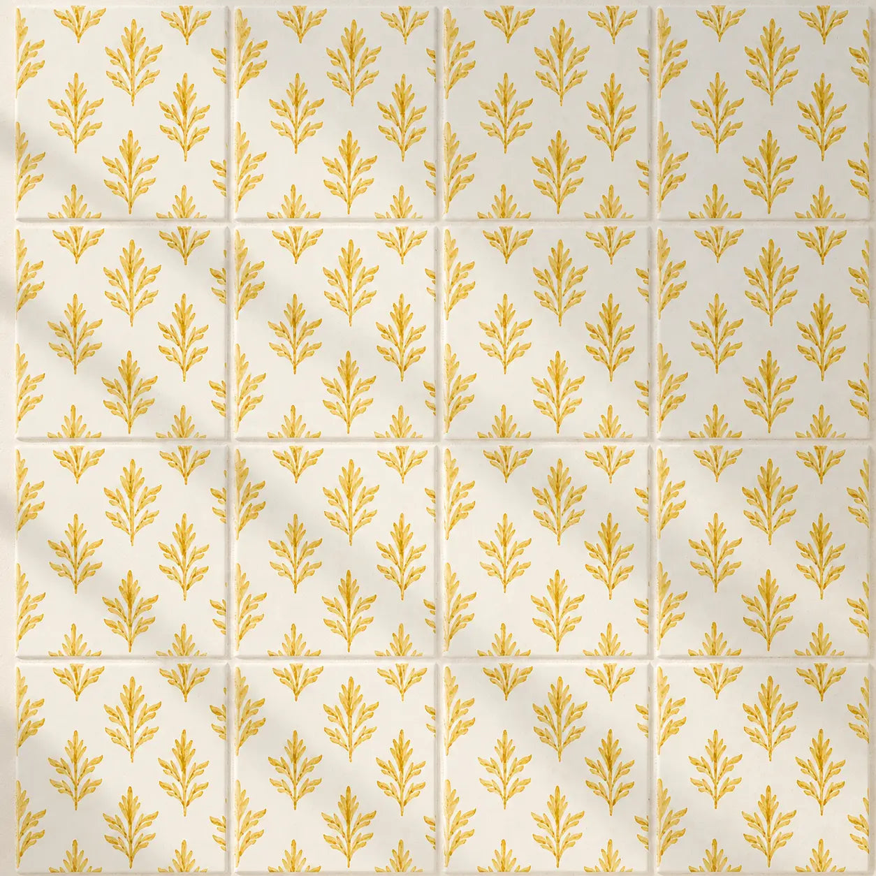 A repeating pattern of square tiles with a warm cream background and a metallic gold botanical leaf motif, arranged in a grid with thin grout lines.