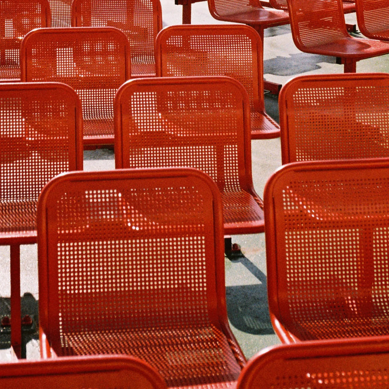 Multiple red perforated metal chairs arranged in rows on a boat floor.