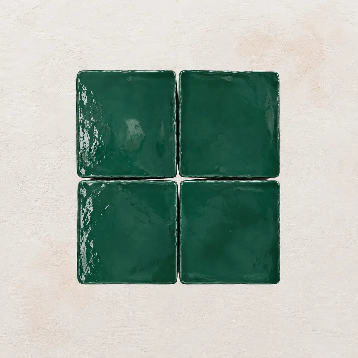 Four emerald green square tiles on a textured beige background
