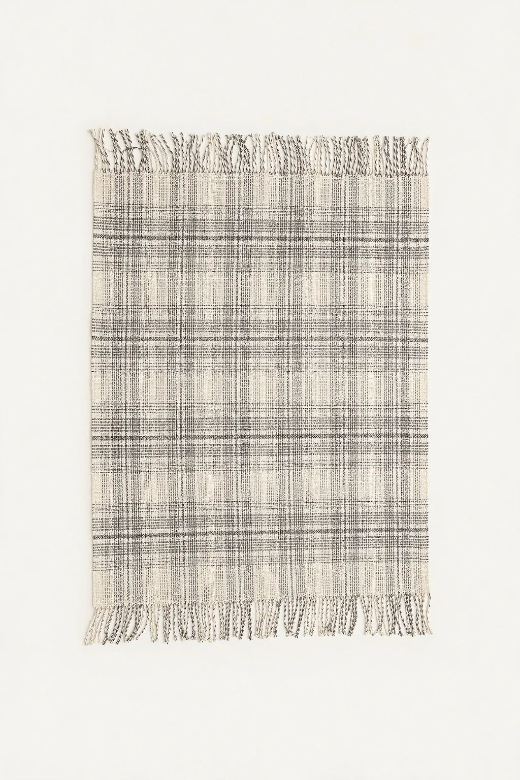 A rectangular woven throw blanket with a plaid pattern in beige, gray, and white, featuring fringed edges on the top and bottom, shown against a plain off-white background.