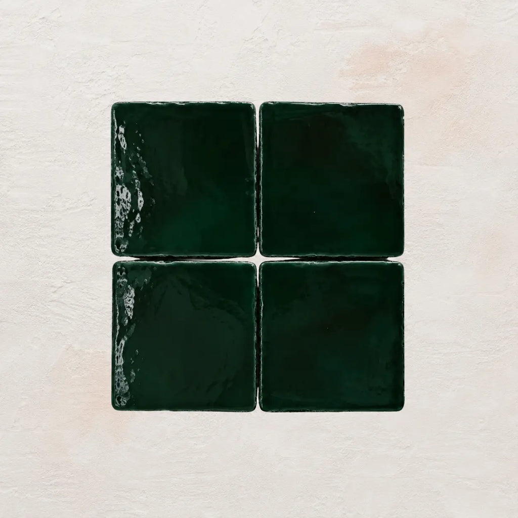 Four forest green square tiles on a textured beige background