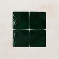 Four forest green square tiles on a textured beige background