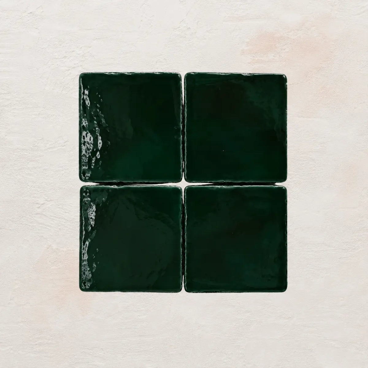 Four forest green square tiles on a textured beige background