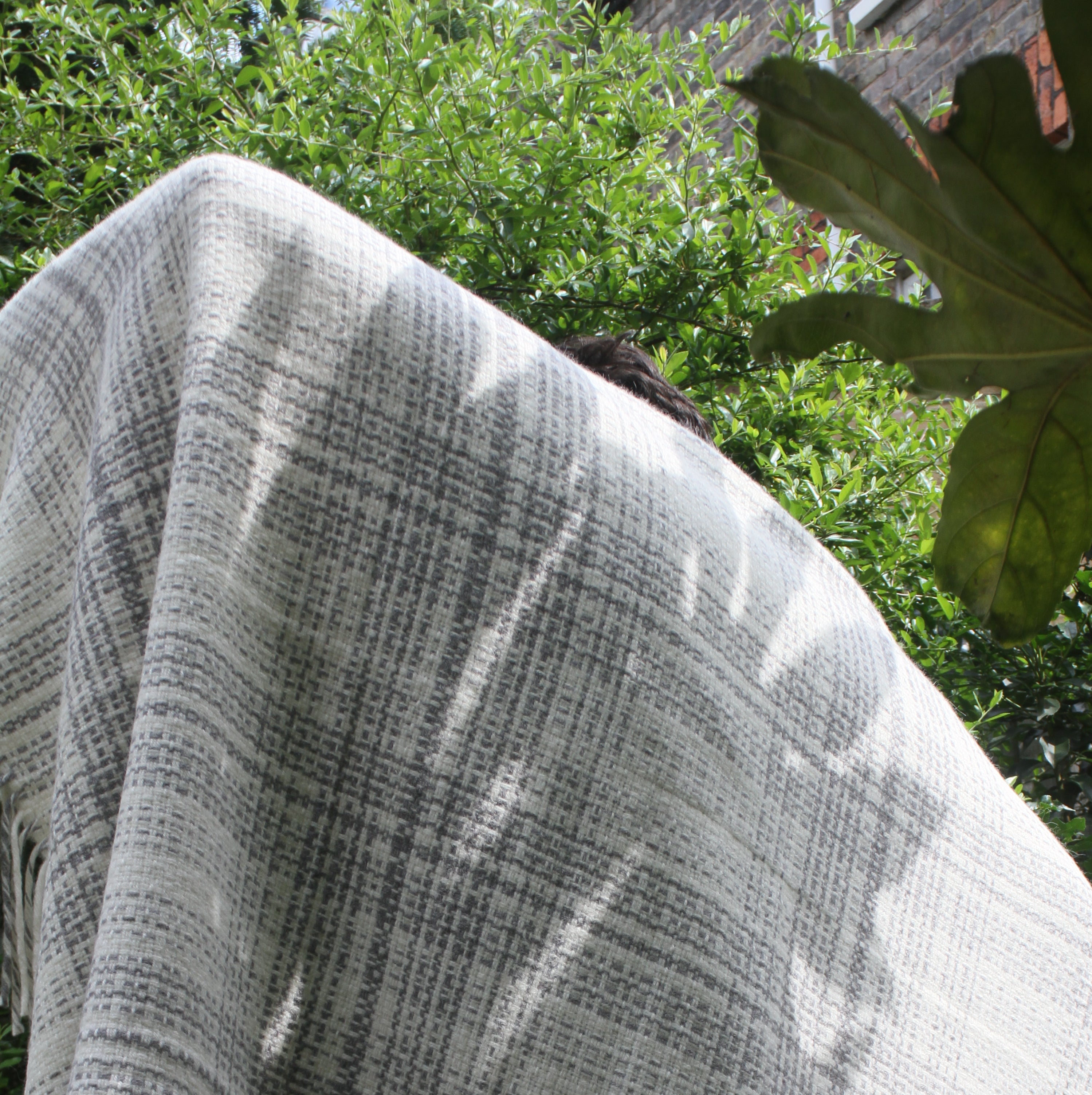 A person holding a graphic monochrome blanket in the garden