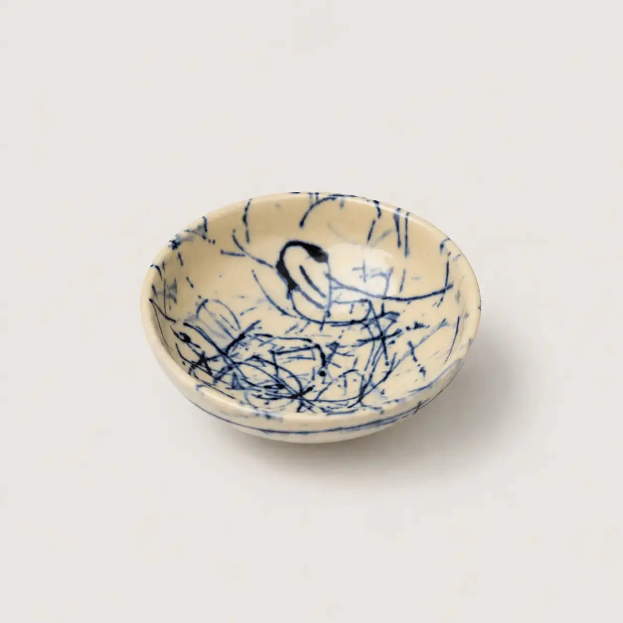 Ceramic snack bowl with blue abstract patterns on a beige background