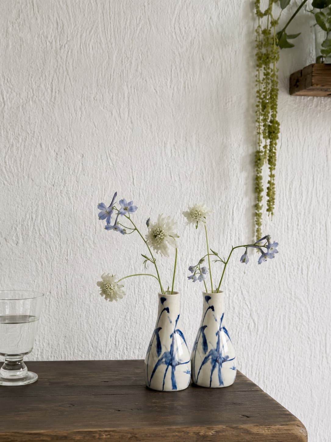 Two small ceramic vases with blue floral patterns on a wooden surface against a white wall.