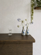 Two small ceramic vases with blue floral patterns on a wooden surface against a white wall.