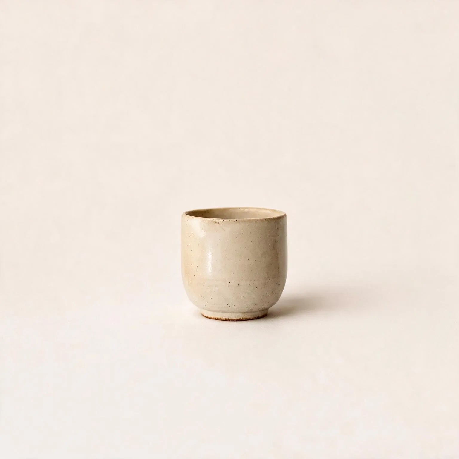 White ceramic cup with gold rim on a matching saucer against a white background