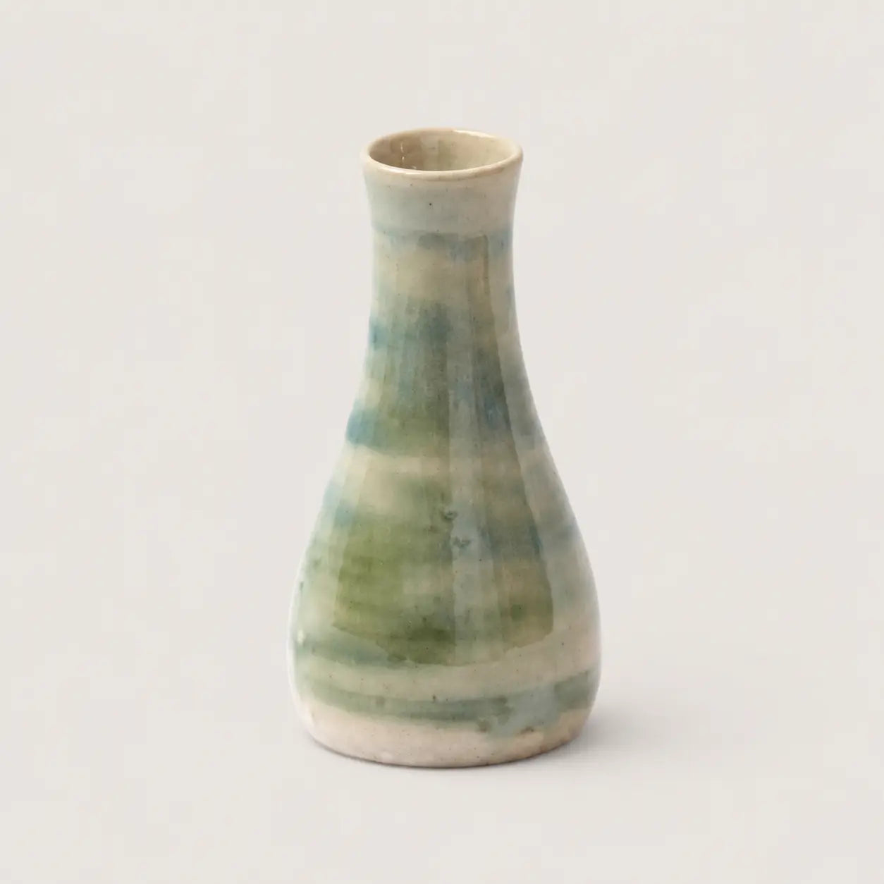 Ceramic vase with green and beige glaze on a light gray background